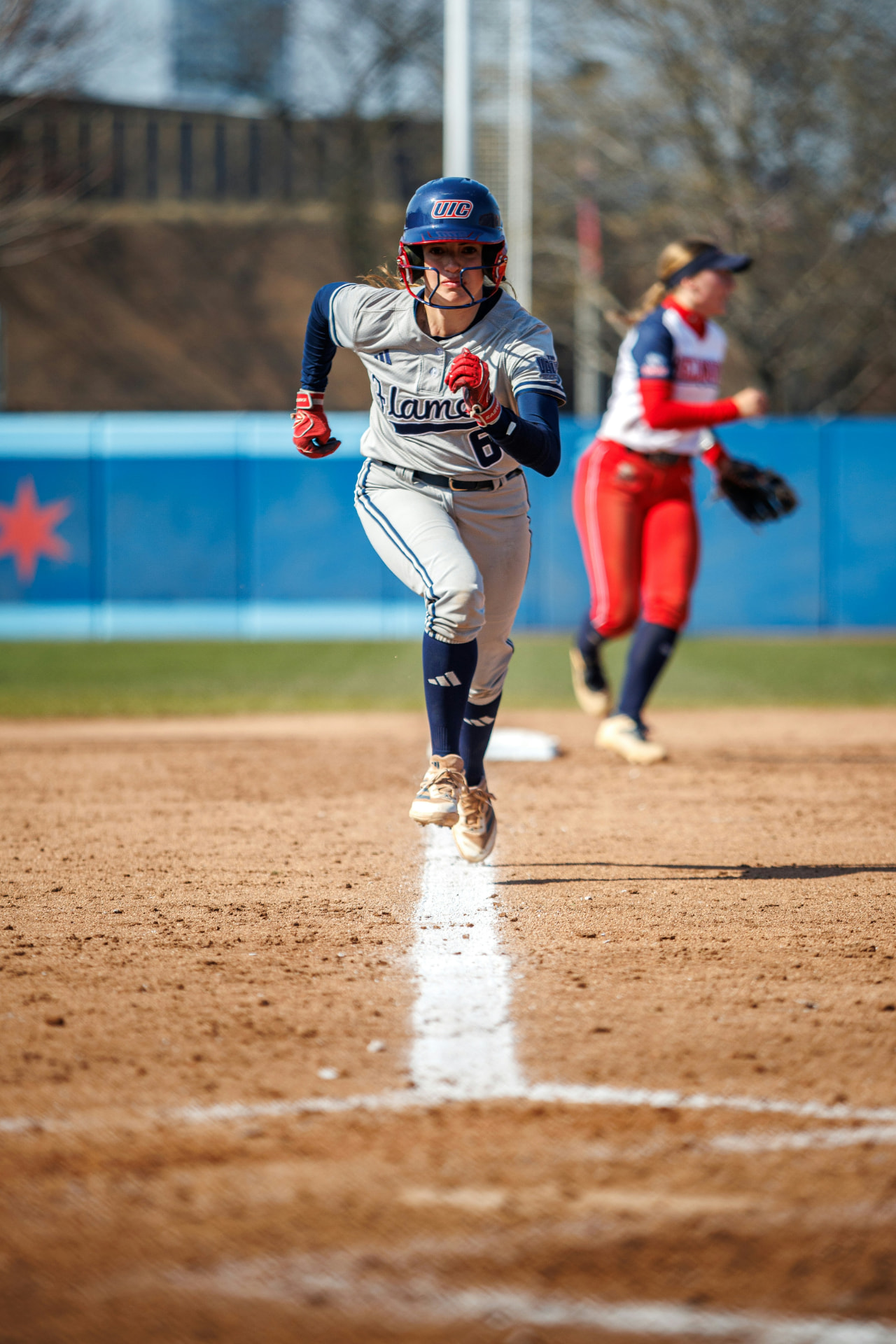 UIC Flames softball baserunner sprinting down the first base line